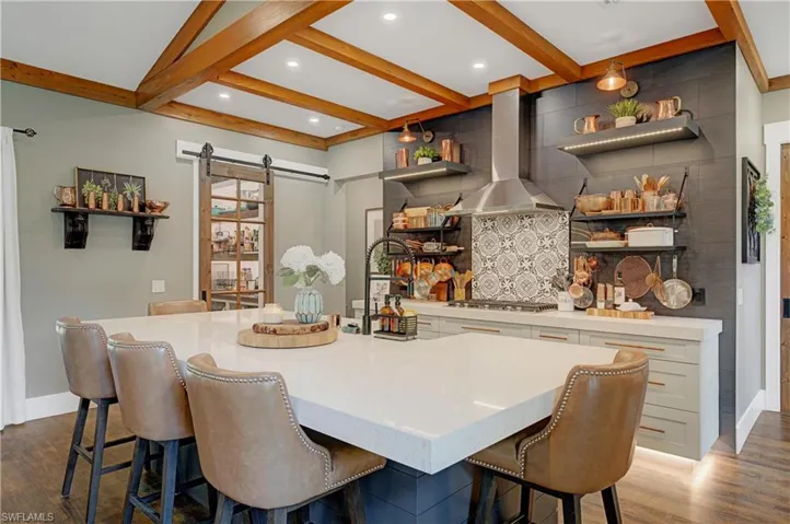 Kitchen with a large island, island exhaust hood, a breakfast bar, and a barn door