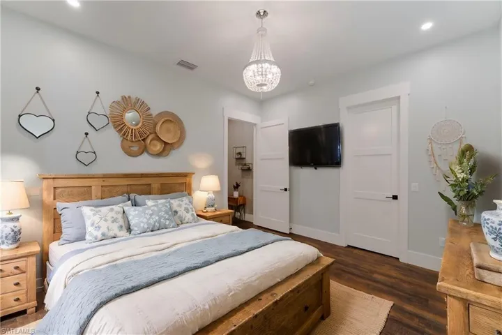 Bedroom featuring dark hardwood / wood-style floors and a notable chandelier - virtually staged