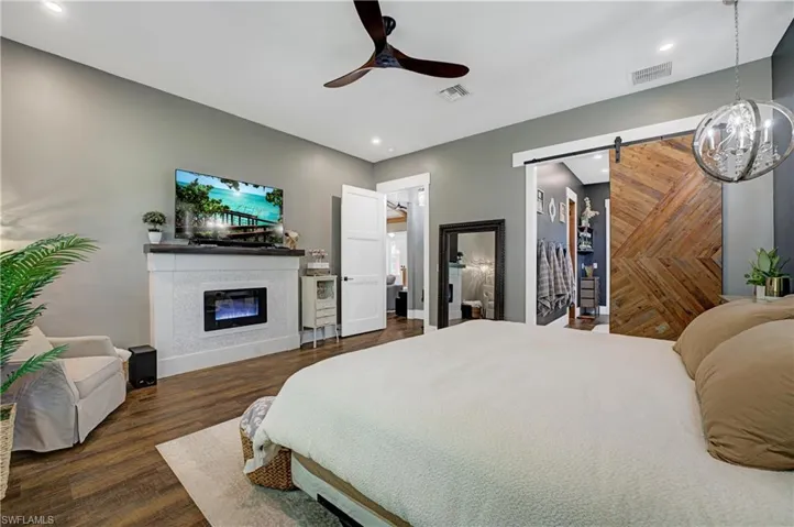 Bedroom with ceiling fan, dark wood-type flooring, and a barn door