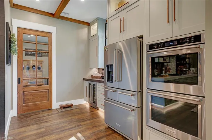 Kitchen featuring beverage cooler, beam ceiling, dark hardwood / wood-style floors, and stainless steel appliances