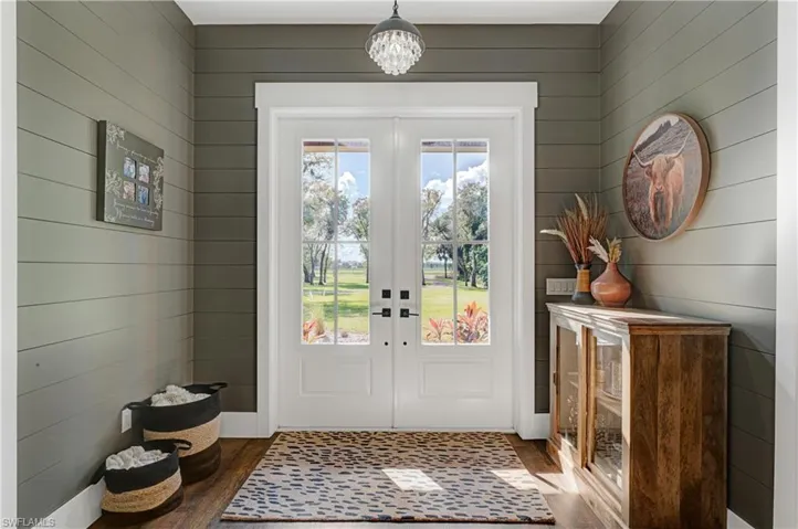 Entryway featuring wood walls, french doors, and dark wood-type flooring
