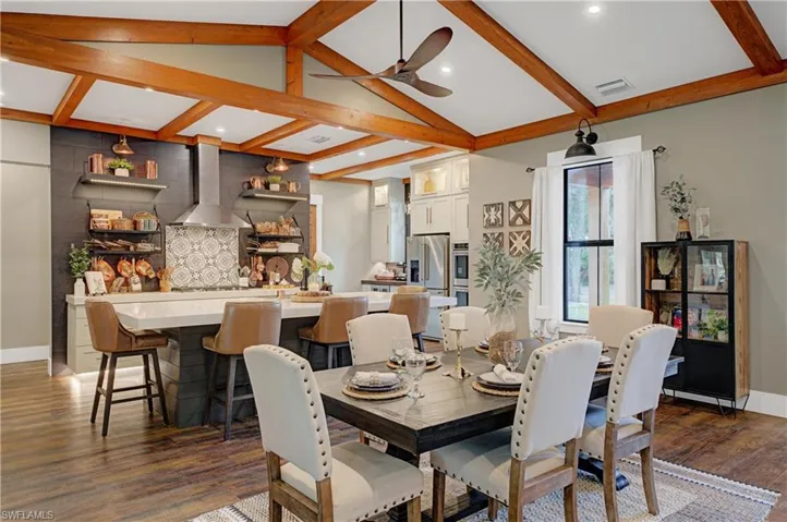 Dining room featuring lofted ceiling with beams, ceiling fan, and dark wood-type flooring
