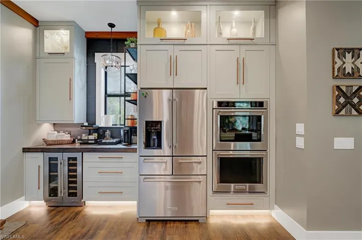 Kitchen featuring hanging light fixtures, stainless steel appliances, wine cooler, dark hardwood / wood-style floors, and a notable chandelier