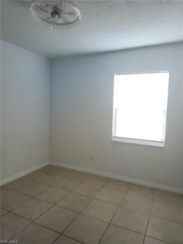 Empty room featuring baseboards and light tile patterned floors