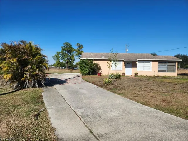 Single story home featuring a front lawn, stucco siding, and concrete driveway
