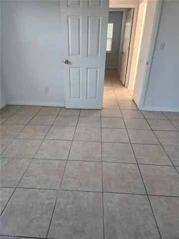 Empty room featuring light tile patterned floors and baseboards