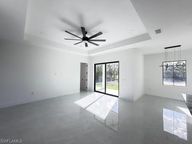 Empty room with ceiling fan and a tray ceiling