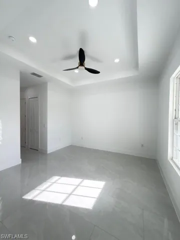 Unfurnished room featuring recessed lighting, ceiling fan, and a tray ceiling
