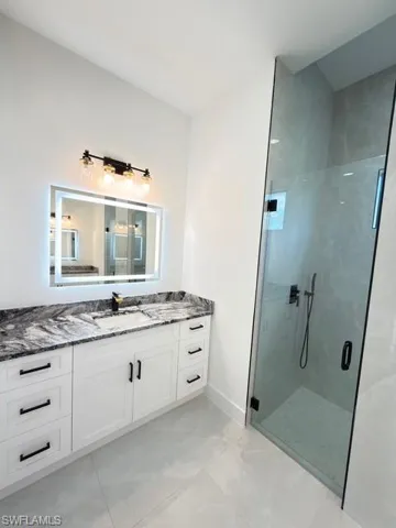 Full bathroom with vanity and a marble finish shower