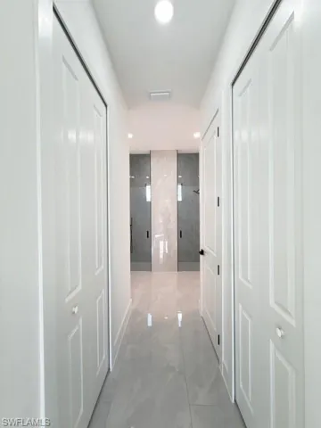 Hallway with light marble finish flooring and recessed lighting