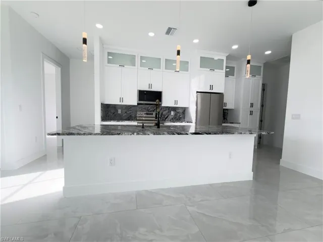 Kitchen featuring white cabinetry, decorative backsplash, stainless steel appliances, and glass fronted cabinets