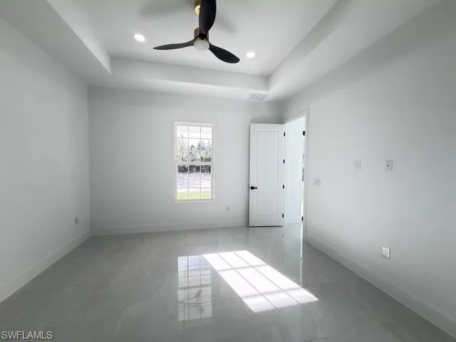 Unfurnished bedroom with a raised ceiling and a ceiling fan