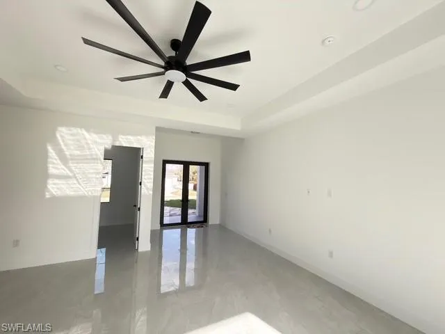 Empty room with french doors, a ceiling fan, and a raised ceiling