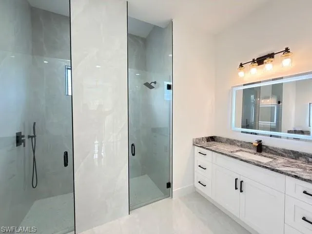 Full bathroom featuring a marble finish shower and vanity