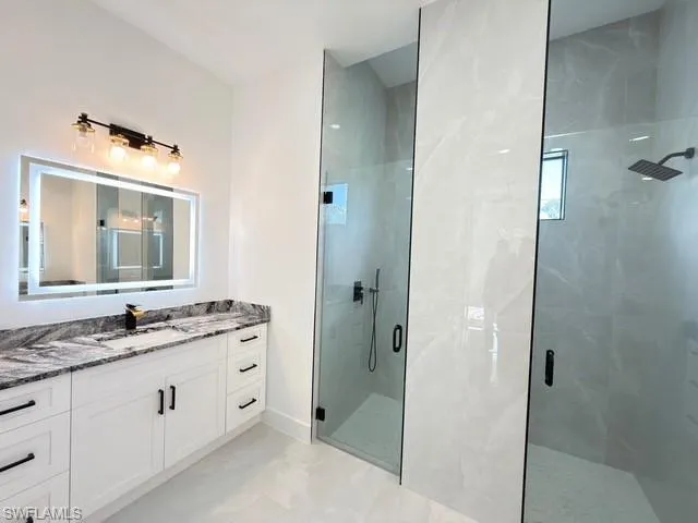 Full bath featuring vanity and a marble finish shower