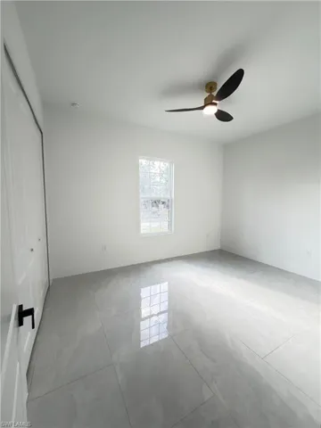 Unfurnished bedroom featuring a closet, ceiling fan, and light tile patterned floors