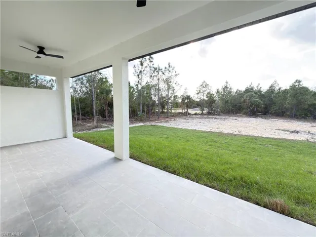 View of patio with a ceiling fan and view of wooded area