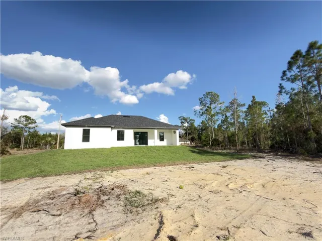 Rear view of house with a lawn, a patio area, and stucco siding