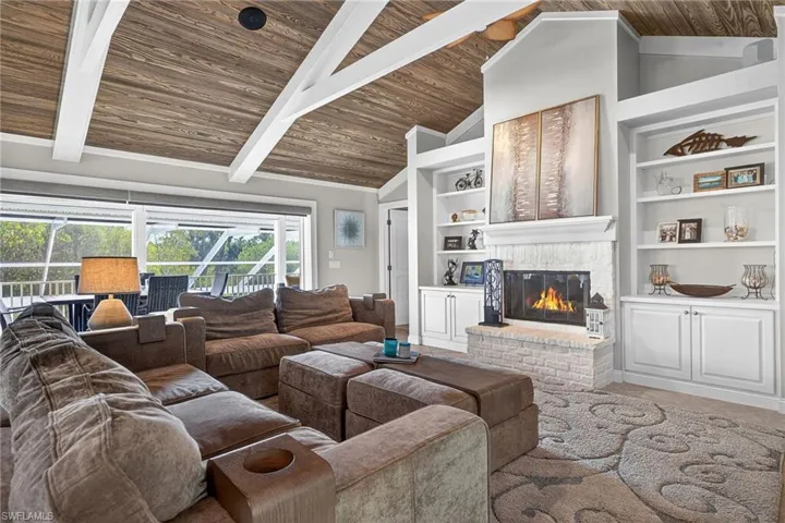 Living room featuring a brick fireplace and a high wood beamed ceiling