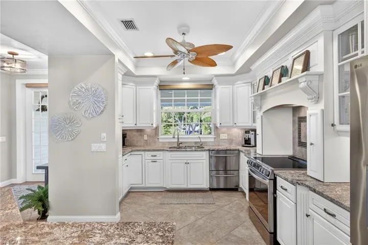 Kitchen featuring light stone countertops, stainless steel appliances, white cabinets, crown molding, and recessed lighting