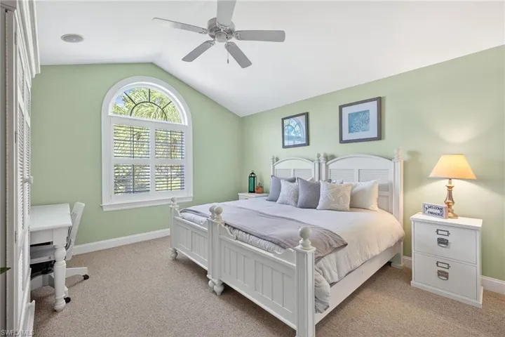 Bedroom featuring light colored carpet, a ceiling fan, and an office area