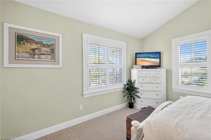 Carpeted bedroom with lofted ceiling and baseboards