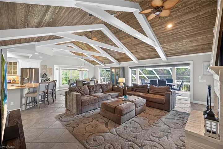 Living area featuring a fireplace, a high wood ceiling, light tile patterned floors, a ceiling fan, and a chandelier