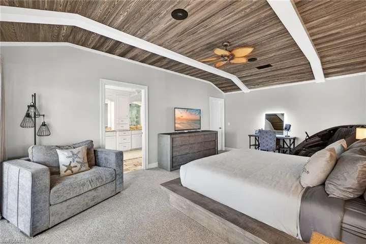 Carpeted bedroom featuring a vaulted wooden ceiling, ceiling fan, crown molding, and connected bathroom