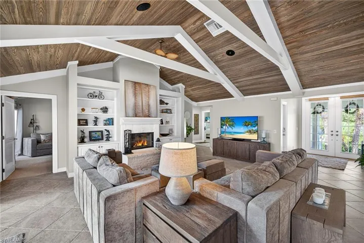 Living room featuring french doors, built in features, a high wooden beamed ceiling, a fireplace, and light tile patterned floors