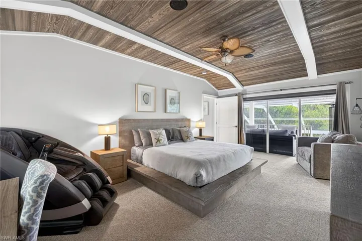 Bedroom with lofted ceiling with beams, carpet floors, a ceiling fan, and wooden ceiling