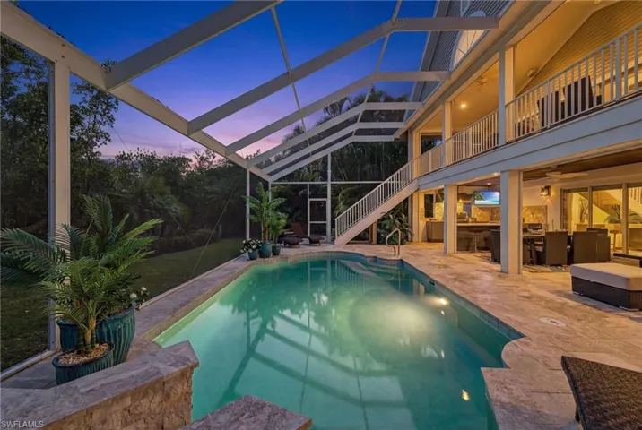 Pool at dusk featuring an outdoor pool, a patio area, a sunroom, and a balcony