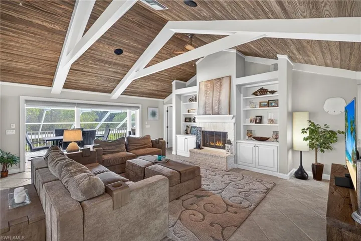 Tiled living area featuring built in shelves, a brick fireplace, and a high wood beamed ceiling