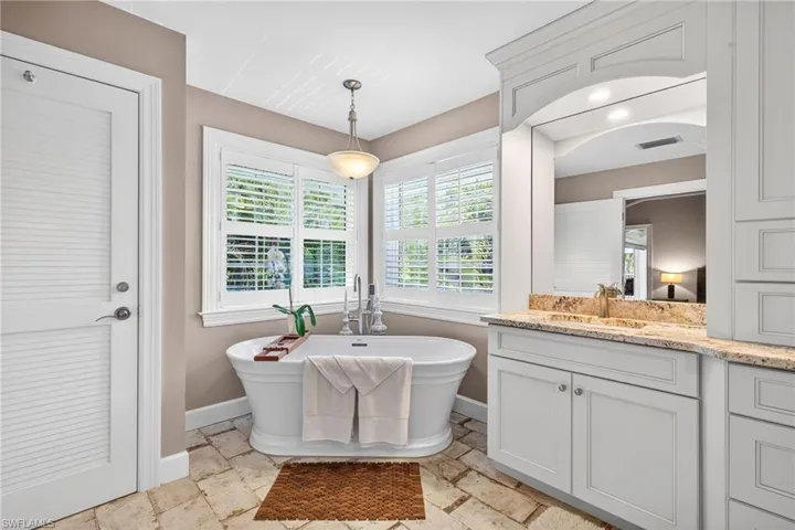 Bathroom with stone tile floors, vanity, and a freestanding bath