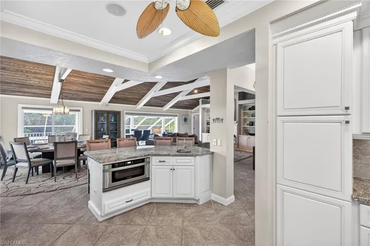 Kitchen with ornamental molding, oven, a ceiling fan, white cabinets, and open floor plan