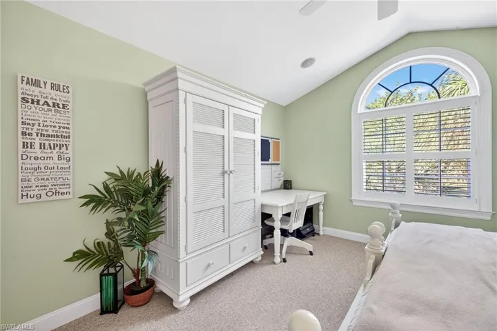 Bedroom featuring light carpet, vaulted ceiling, and a ceiling fan