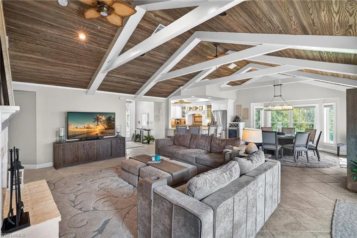 Living room featuring ceiling fan, a high wooden beamed ceiling, a chandelier, and tile patterned floors
