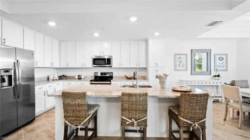 Kitchen with sink, stainless steel appliances, a kitchen island with sink, and a kitchen breakfast bar