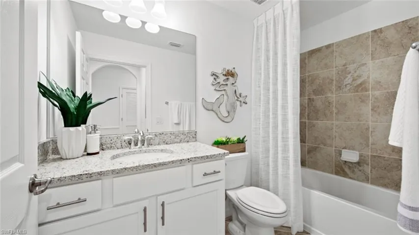 Full bathroom featuring toilet, shower / tub combo, and vanity