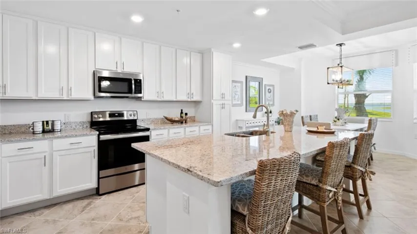 Kitchen featuring sink, white cabinets, appliances with stainless steel finishes, and a kitchen island with sink