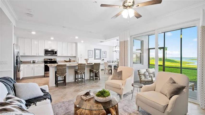 Living room featuring ceiling fan with notable chandelier, light tile patterned floors, and ornamental molding