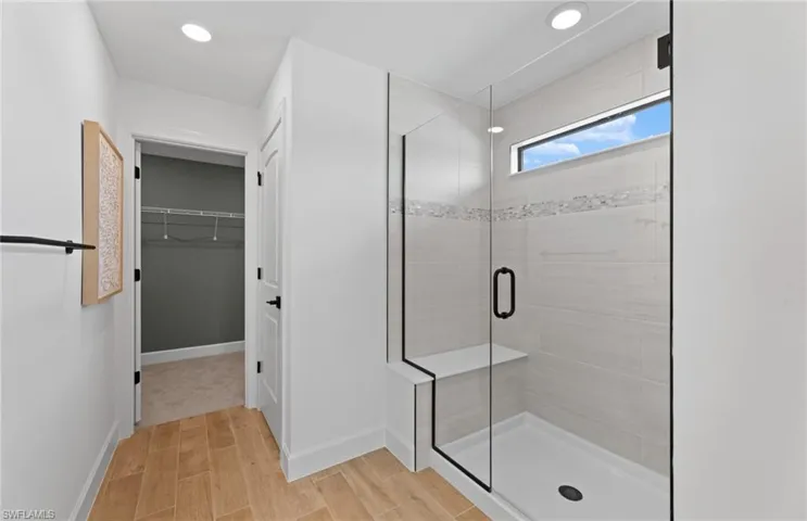 Full bath featuring a spacious closet, a stall shower, wood finish floors, and recessed lighting