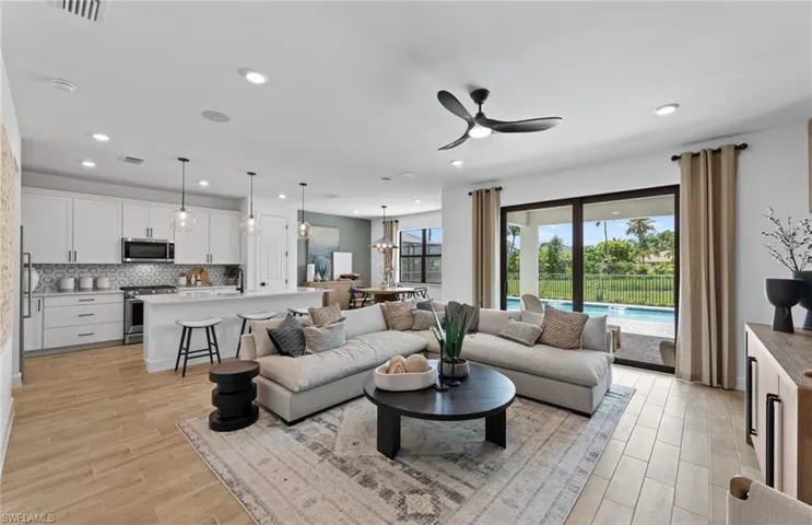 Living area with light wood-type flooring, ceiling fan, and suspended lighting