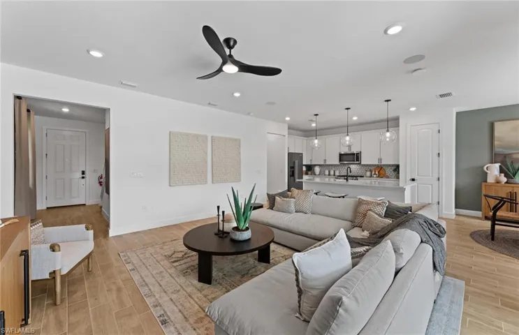 Living area with wood tiled floors, a ceiling fan, and recessed lighting