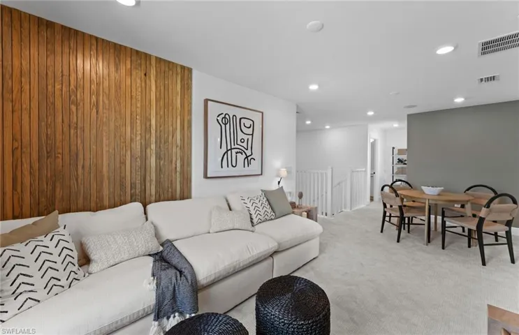 Carpeted living room featuring recessed lighting and wooden walls