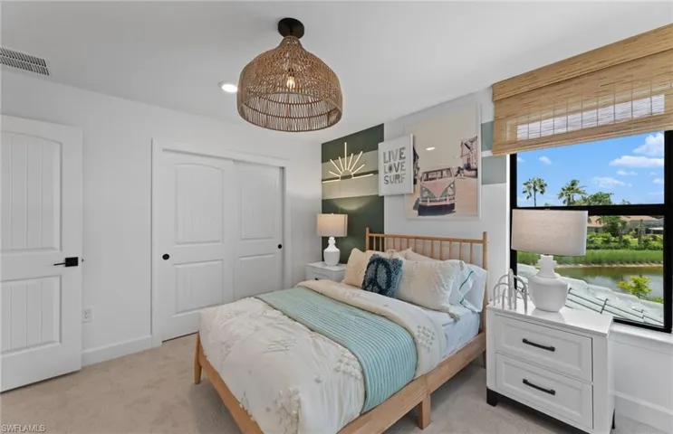 Bedroom featuring a closet, light colored carpet, and suspended lighting