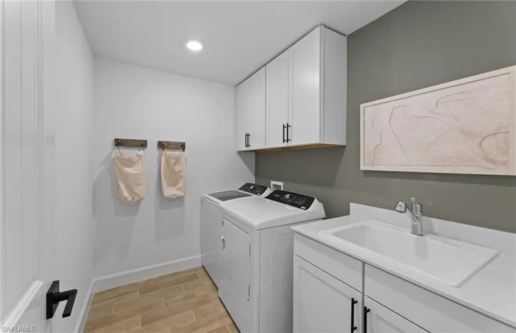Laundry area featuring cabinet space, wood tiled floors, washing machine and clothes dryer, and recessed lighting