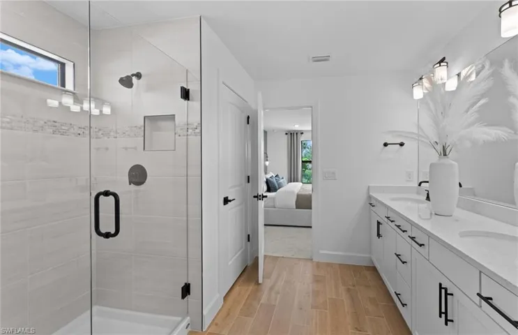 Ensuite bathroom with double vanity, a stall shower, and wood tiled floors