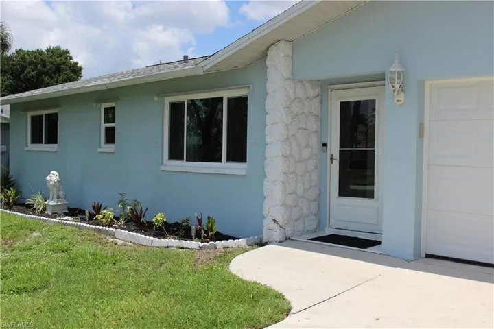 Doorway to property featuring a garage and a yard