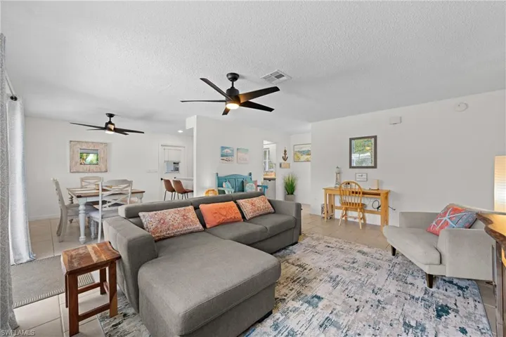 Tiled living room with a ceiling fan and a textured ceiling