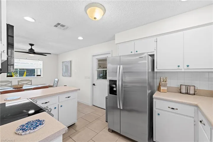 Kitchen featuring stainless steel refrigerator with ice dispenser, light countertops, light tile patterned floors, white cabinets, and recessed lighting